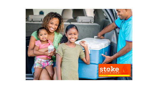 A diverse group of families hiking on a scenic trail, with children enjoying beef sticks, surrounded by lush forests and clear blue skies.