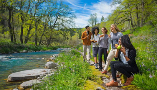 A diverse group of young adults enjoy an outdoor adventure in a scenic national park, highlighting healthy snacking with grass-fed beef jerky.