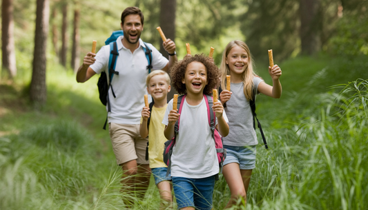 A family hiking in a forest with children holding snack sticks, showcasing adventure and healthy snacking.
